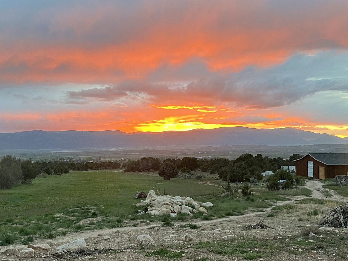 The view at sunset from the Rencher Residence — a custom-designed home on 40 acres outside Spring City, Utah, surrounded by sagebrush and junipers with the Sanpete Valley mountains in the background